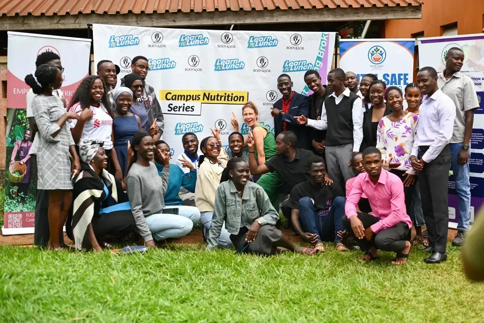 Students, Learn And Lunch and BODY & SOIL team members in front of the Campus Nutrition Series banner at Kyambogo University